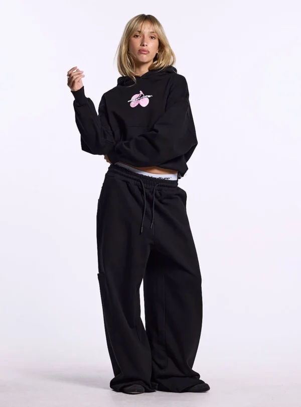 Modelo de cuerpo entero con sudadera negra Cold Culture Berry vista frontal con gráfico de cerezas rosas en el pecho