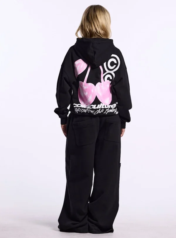Modelo de cuerpo entero con sudadera negra Cold Culture Berry de espaldas mostrando el estampado de cerezas rosas