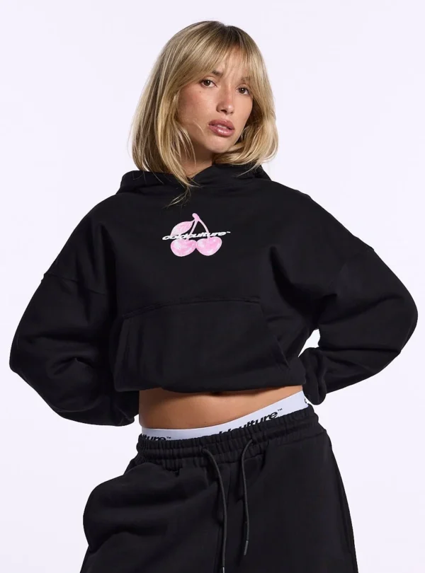 Modelo con sudadera negra Cold Culture Berry mostrando el gráfico de cerezas rosas en el pecho y bolsillo canguro