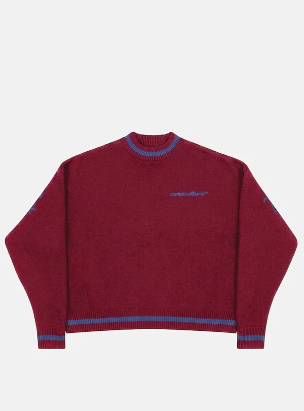 Vista frontal del jersey Archive Gothic Knit Red de Cold Culture en rojo burdeos, con pequeño logotipo azul en el pecho y detalles de rayas azules en cuello, puños y bajo.