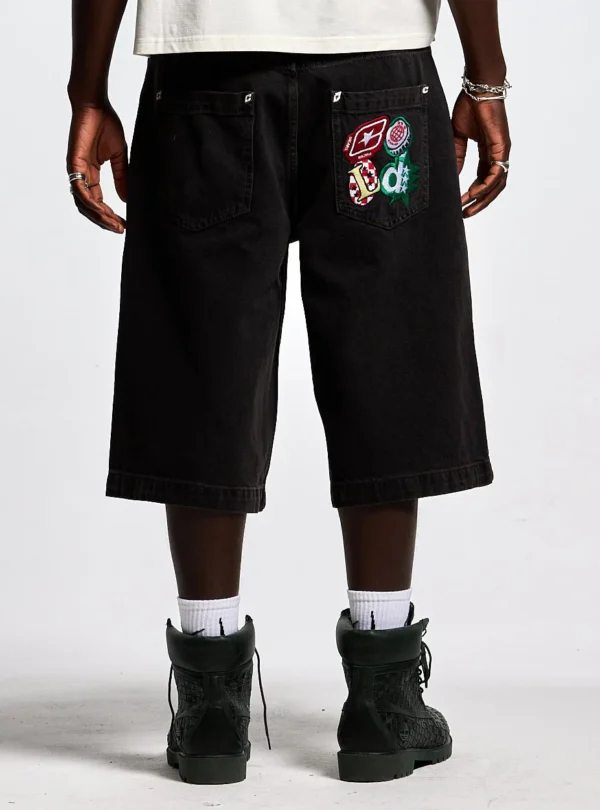 Modelo con shorts Badges Jorts de Cold Culture en Black Licorice, vista trasera con parches gráficos en el bolsillo