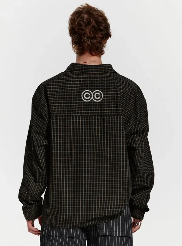 Modelo de espaldas con la camisa Brick Lane de Cold Culture en color Black Square, mostrando el corte holgado, el estampado de cuadros y el logotipo trasero