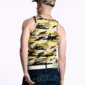 Modelo de espaldas con la camiseta de tirantes Camo Tank Top amarilla de Cold Culture, con estampado de camuflaje, combinada con gorra y vaqueros oscuros