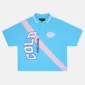 Polo Cocky azul de Cold Culture con franja diagonal rosa, letras grandes en el frontal, cuello con ribete blanco y manga corta.
