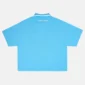 Vista trasera del polo Cocky azul de Cold Culture, con diseño liso, logotipo blanco bajo el cuello y mangas cortas de corte amplio.