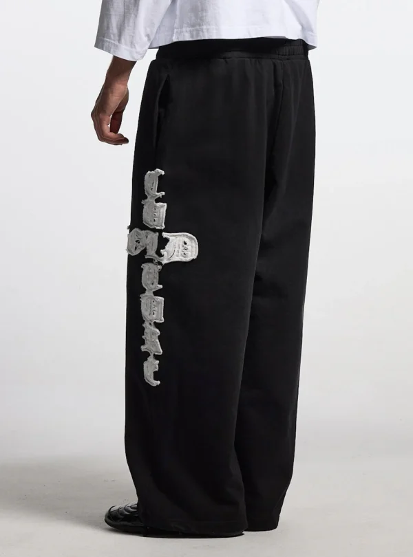 Vista posterior de modelo con pantalones deportivos negros Cold Culture Crossed y gráfico blanco en la pernera