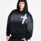 Modelo con sudadera Crossed Black de Cold Culture, capucha puesta, gráfico blanco de cruz en el pecho, mangas amplias y bolsillo canguro.