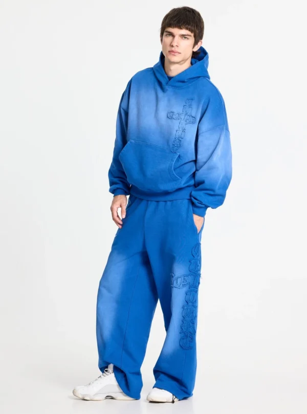 Modelo con sudadera Crossed azul de Cold Culture en vista de tres cuartos, con capucha amplia, efecto degradado y cruz en relieve.