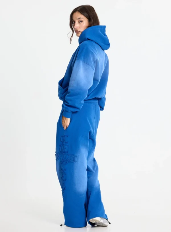 Modelo con sudadera Crossed azul de Cold Culture, vista lateral trasera con capucha y mangas holgadas.