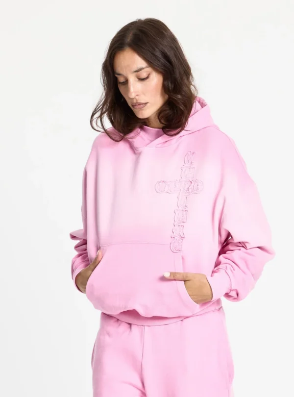 Cold Culture Crossed Sudadera Pink – Vista frontal con modelo y bolsillo canguro Modelo con la sudadera rosa Crossed de Cold Culture, con las manos en el bolsillo canguro y diseño de cruz bordado en el pecho.