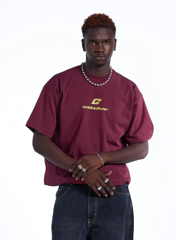 Modelo con camiseta Cold Culture Curved en burdeos y amarillo, mostrando el logotipo amarillo en el pecho