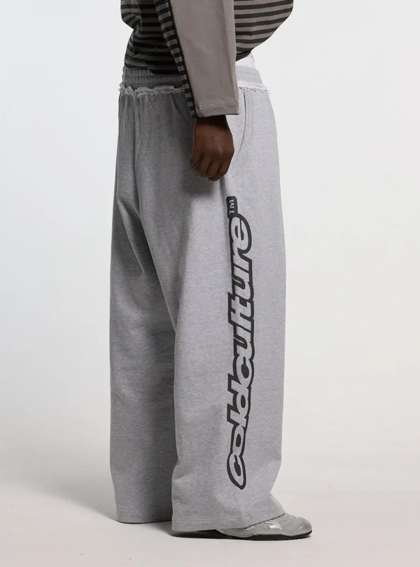 Detalle lateral de los pantalones deportivos Cold Culture Daily Set en Grey Melange con logotipo vertical negro y cintura elástica
