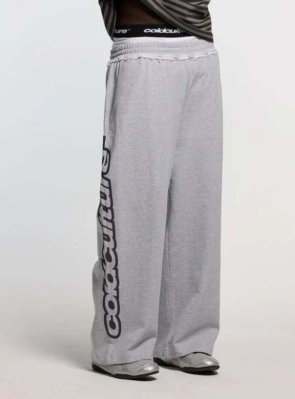Detalle frontal de los pantalones deportivos Cold Culture Daily Set en Grey Melange con logotipo negro vertical en la pernera
