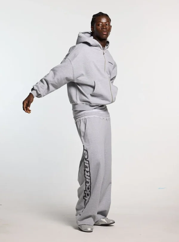 Modelo luciendo los pantalones deportivos Cold Culture Daily Set en Grey Melange de perfil, con logotipo vertical en la pernera
