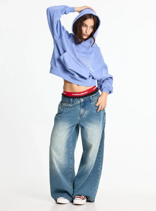 Modelo con pantalones holgados azules Cold Culture Distress Curved de frente, con lavado desgastado y detalles metálicos