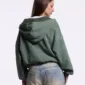 Mujer con sudadera con cremallera verde Eagle de Cold Culture vista desde atrás, con capucha y diseño trasero liso