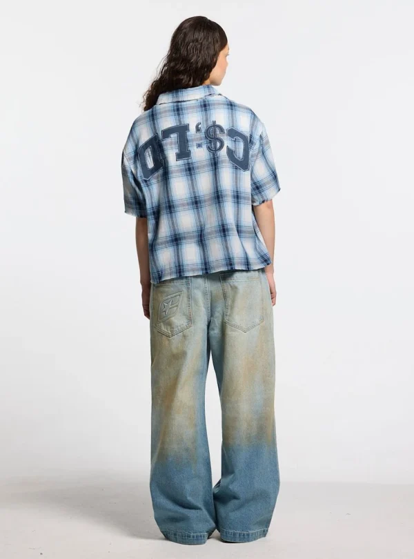 Modelo de espaldas con camisa Farm de Cold Culture de cuadros blancos y azules, corte holgado y gráfico bordado de gran tamaño en la espalda