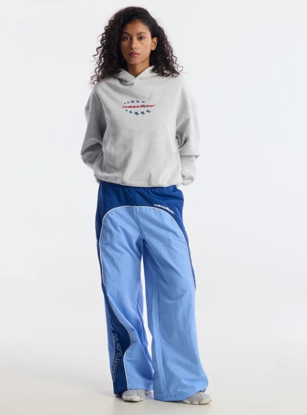 Modelo de cuerpo entero con sudadera Fourth Of July de Cold Culture en gris jaspeado y pantalones azules, mostrando el ajuste holgado, el bolsillo canguro y el estampado frontal.