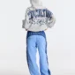 Modelo de cuerpo entero de espaldas con sudadera Fourth Of July de Cold Culture en gris jaspeado y capucha puesta, mostrando el estampado trasero de letras azules y estrellas.