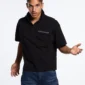 Modelo luciendo el Gilded Polo negro de Cold Culture en una vista frontal cercana que destaca los dos bolsillos de solapa y el logotipo en el pecho.