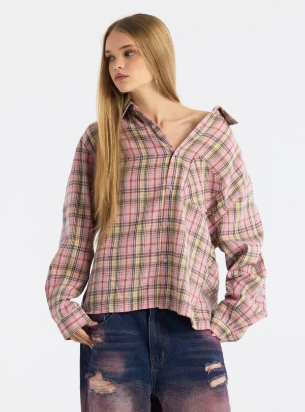 Modelo con camisa Gleenwood Plaid Tartan rosa de Cold Culture, de cuadros, manga larga y corte holgado, con el cuello abierto y un hombro descubierto.