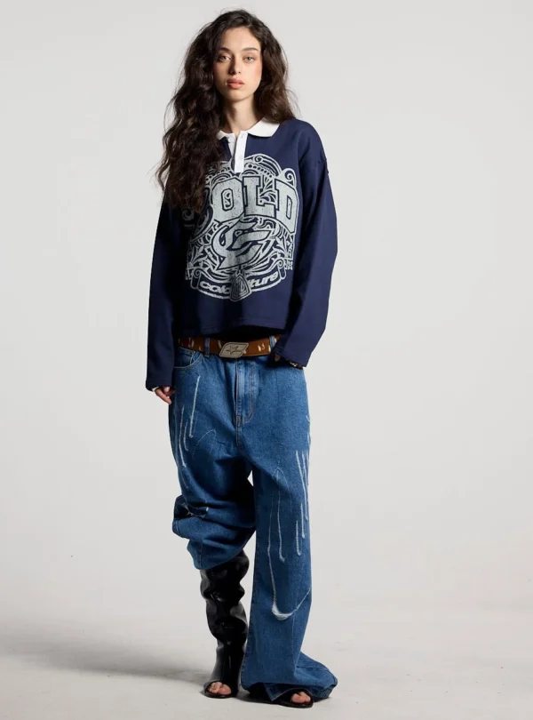 Modelo de cuerpo entero con el Good Boy Polo de Cold Culture en azul oscuro, combinado con vaqueros anchos y botas negras.