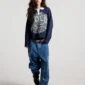 Modelo de cuerpo entero con el Good Boy Polo de Cold Culture en azul oscuro, combinado con vaqueros anchos y botas negras.