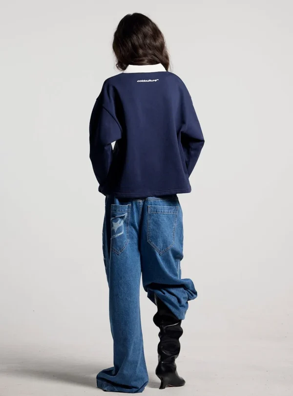 Modelo de cuerpo entero de espaldas con el Good Boy Polo de Cold Culture en azul oscuro, mostrando la caída holgada y el logotipo bajo el cuello blanco.