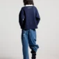 Modelo de cuerpo entero de espaldas con el Good Boy Polo de Cold Culture en azul oscuro, mostrando la caída holgada y el logotipo bajo el cuello blanco.