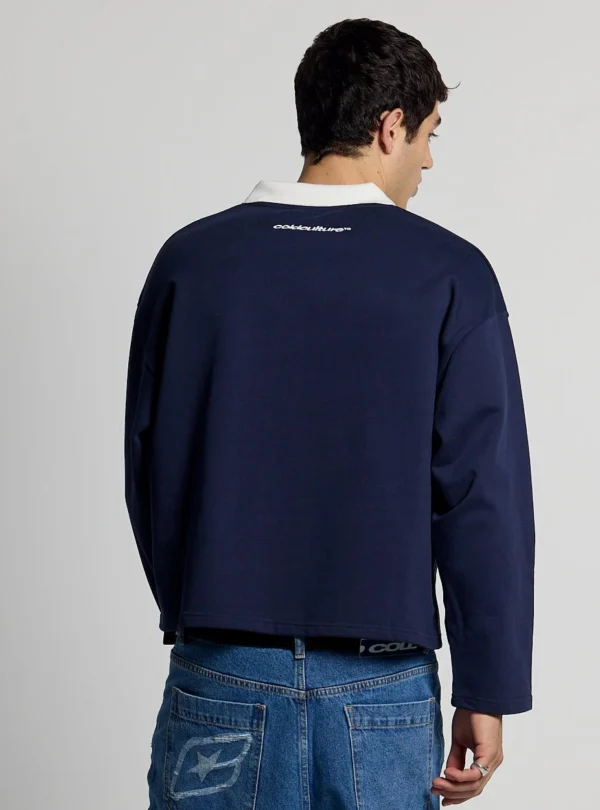 Modelo de espaldas con el Good Boy Polo de Cold Culture en azul oscuro, mostrando el corte holgado y el pequeño logotipo blanco en la parte superior.