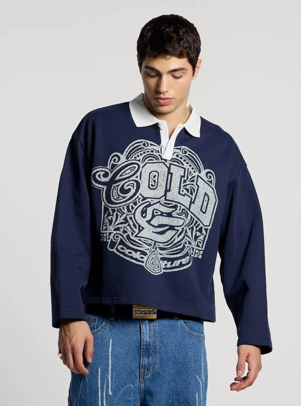 Modelo con el Good Boy Polo de Cold Culture en azul oscuro, mostrando su corte holgado, cuello blanco y estampado gráfico gris en el pecho.