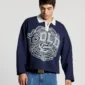 Modelo con el Good Boy Polo de Cold Culture en azul oscuro, mostrando su corte holgado, cuello blanco y estampado gráfico gris en el pecho.