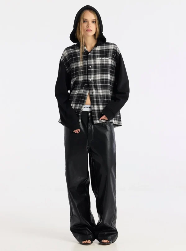 Modelo de cuerpo entero con la camisa Highland Fade negra de Cold Culture, con cuadros blancos y grises, capucha y botones parcialmente abiertos, combinada con pantalones negros anchos.