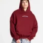 Modelo con sudadera Holeshot Burgundy de Cold Culture, capucha puesta, corte holgado, bolsillo canguro y logotipo en el pecho.