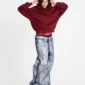 Modelo luciendo la sudadera Holeshot Burgundy de Cold Culture con corte holgado y bolsillo canguro, mientras se ajusta la capucha.