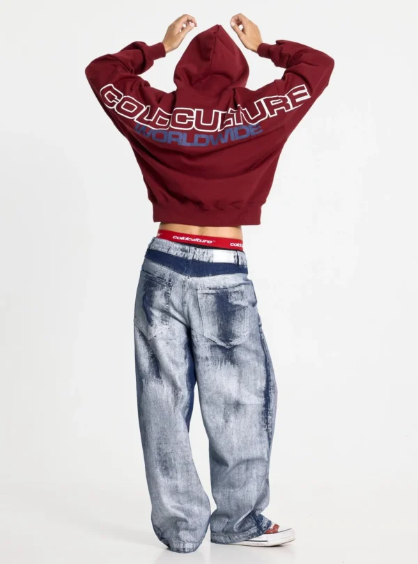 Modelo de espaldas con sudadera Holeshot Burgundy de Cold Culture, brazos levantados y estampado Worldwide en la parte superior de la espalda.