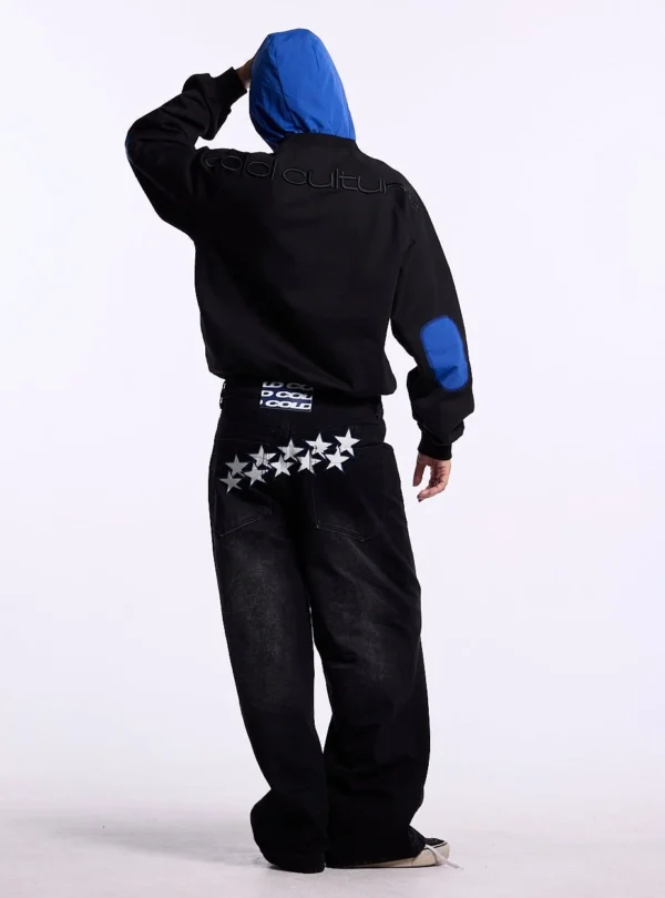 Modelo con sudadera sin capucha Cold Culture Intercept en negro y azul marino, mostrando el logotipo bordado en la espalda y la codera azul
