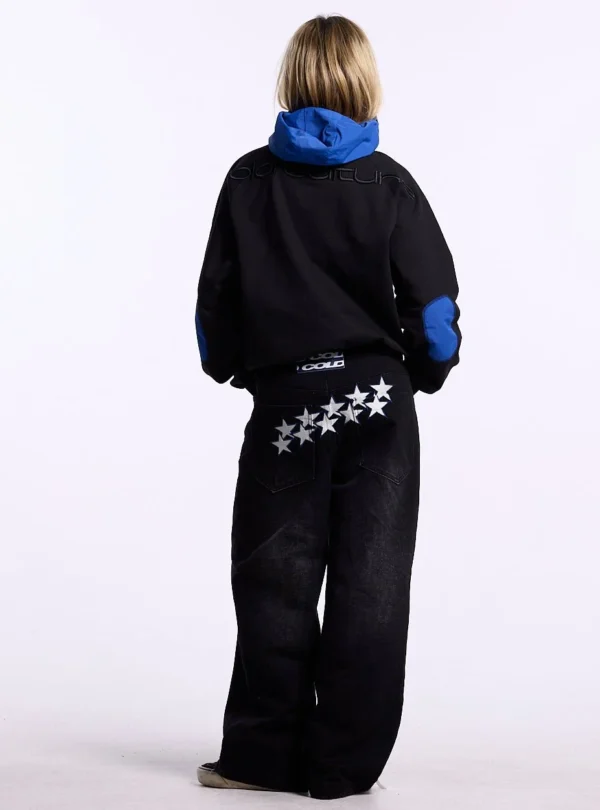 Vista trasera en modelo de la sudadera sin capucha Cold Culture Intercept en negro y azul marino, con capucha azul y logotipo bordado