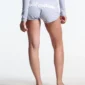 Primer plano trasero de los shorts Lace Mini de Cold Culture en gris jaspeado sobre una modelo, con logotipo blanco en relieve y bajos curvados.