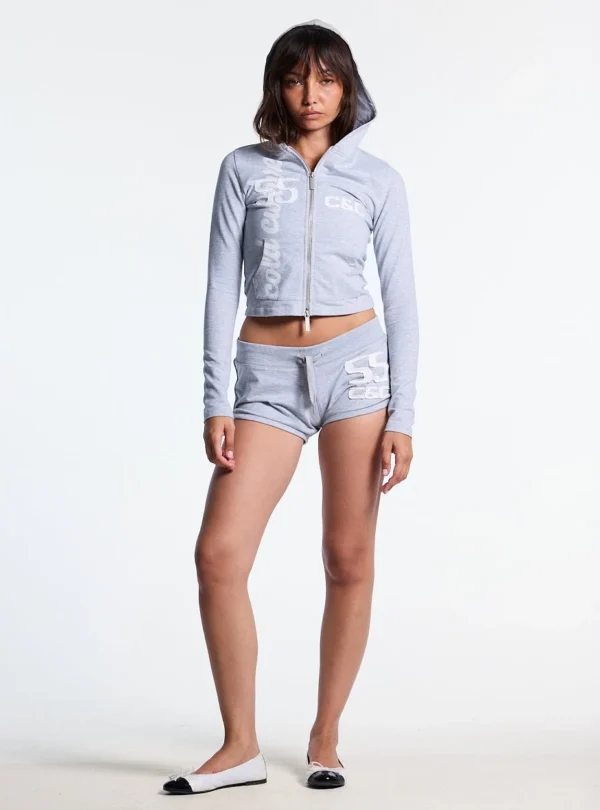 Cold Culture Lace Mini Shorts Heather Grey Mujer – Look frontal con modelo Modelo de frente con los shorts Lace Mini de Cold Culture en gris jaspeado y gráfico blanco, combinados con una sudadera corta con capucha a juego.