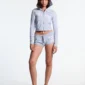 Modelo de frente con los shorts Lace Mini de Cold Culture en gris jaspeado y gráfico blanco, combinados con una sudadera corta con capucha a juego.