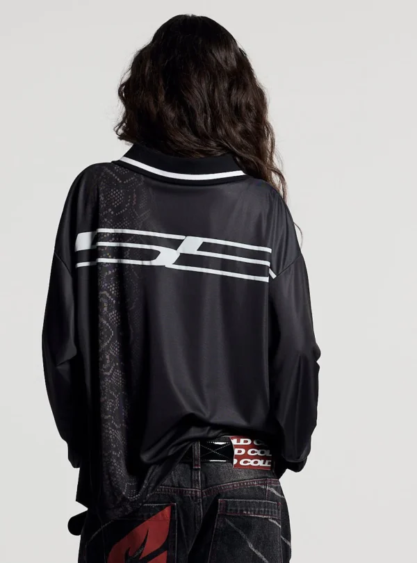 Modelo femenina de espaldas con el Mamba Snake Longsleeve Polo negro de Cold Culture, mostrando el gráfico blanco horizontal y el estampado de serpiente en la parte trasera.
