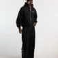 Modelo con pantalones deportivos negros Cold Culture Midnight Set de pernera ancha y logotipo vertical