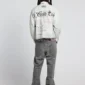 Modelo de espaldas con la camisa Newspaper blanca de Cold Culture, con estampado de periódico negro y logotipo CC en la parte superior