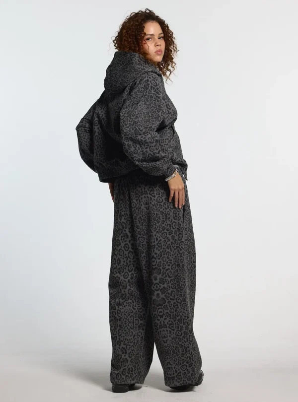 Vista lateral de modelo con pantalones deportivos Cold Culture Nocturne Beast en Dark Grey con estampado animal