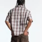 Modelo de espaldas con la Office Script Camisa beige de Cold Culture, de manga corta y cuadros, combinada con pantalón cargo marrón