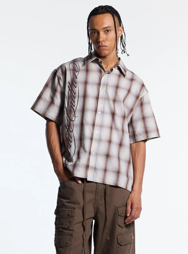 Modelo de frente con la Office Script Camisa beige de Cold Culture, con botones, estampado de cuadros y logotipo vertical, combinada con pantalón cargo marrón