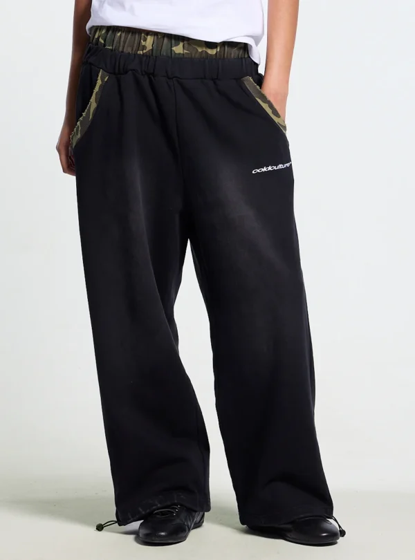Detalle de los pantalones deportivos Cold Culture OPS negros con cintura de camuflaje, bolsillos ribeteados y logotipo blanco