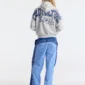 Vista de espalda de un modelo con pantalones deportivos Overcut de Cold Culture en azul, con estampado CULTURE COLD en la parte trasera y los laterales, combinados con una sudadera gris.