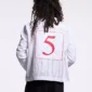 Primer plano de la espalda del polo blanco Pause Longsleeve Polo de Cold Culture, con un número 5 rojo enmarcado y grandes letras grises de fondo.